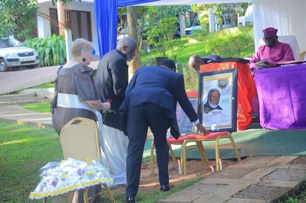 Rev. Dan Kajumba and other family members lay a wreath before the portrait of their late father. Image