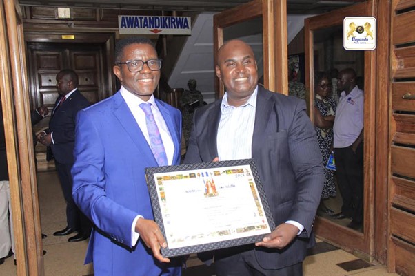 One of the commissioners at URA receiving a certificate from the Buganda prime minister Image