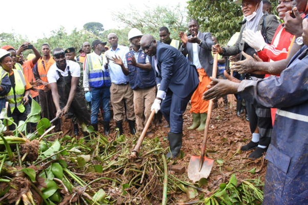 Min. Robert Waggwa Nsibirwa holding a rake leading the cleanup. Image