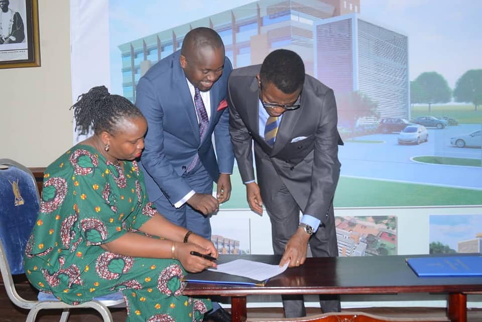 The katikkiro on the left reading through the agreement before the healthy minister signed it. Image