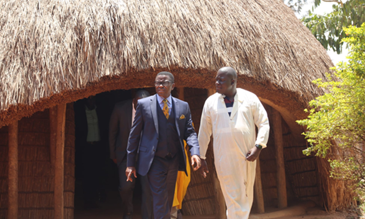 Katikkiro (left) walking out of the Kasubi Royal Tombs. Image